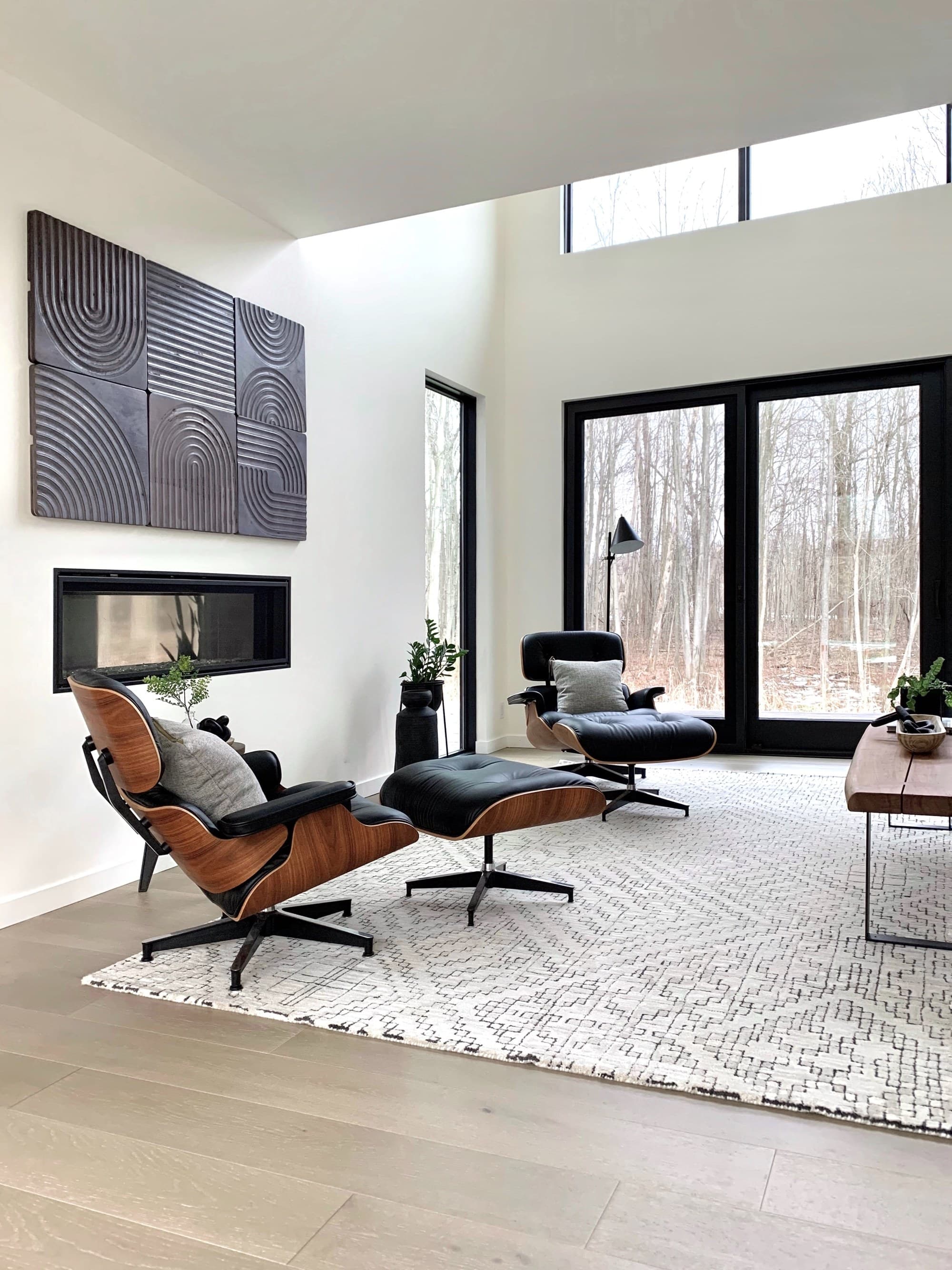Double-height living room with lounge chairs and a linear fireplace